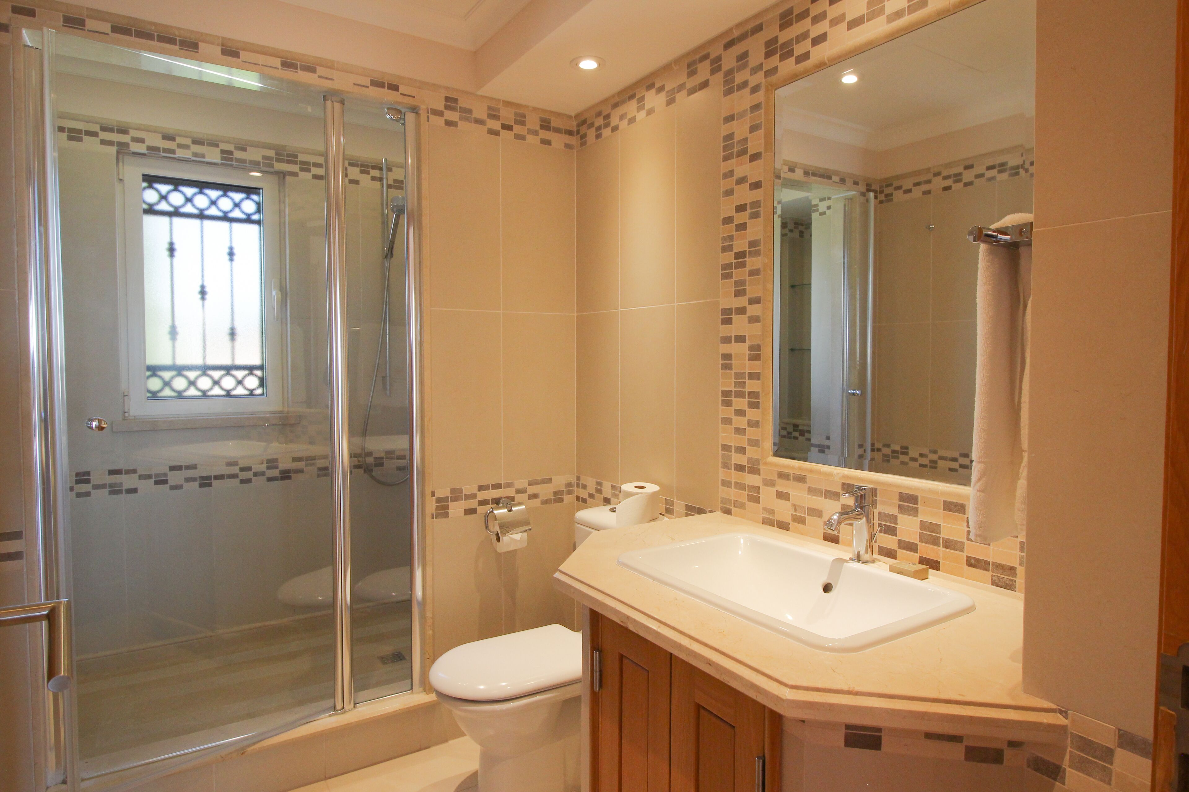 A bathroom with a glass-enclosed shower, a toilet, a sink, and a mirror.