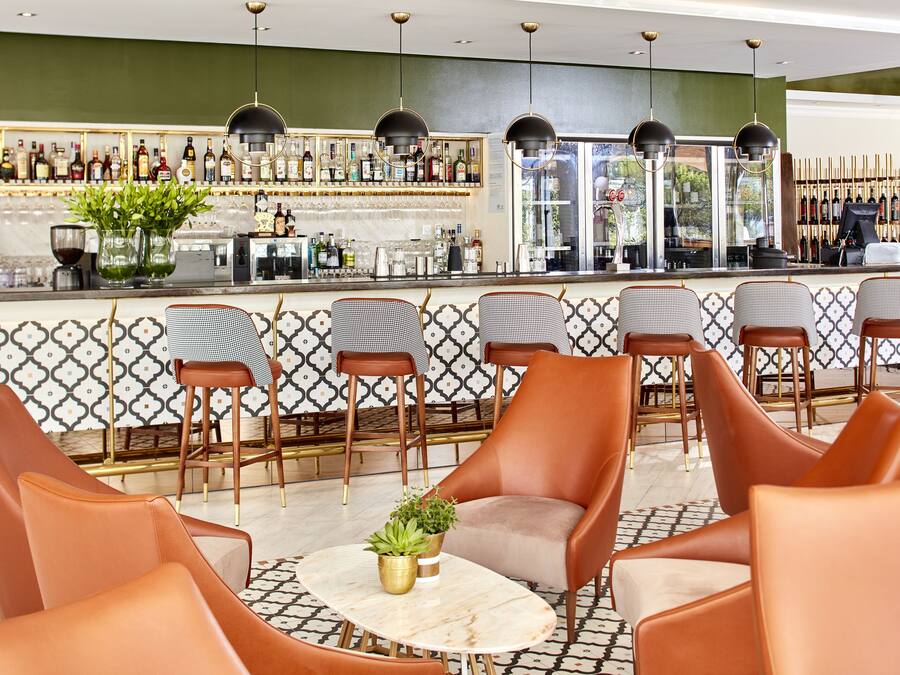 Eine Bar mit verschiedenen Sitzgelegenheiten, darunter Stühle und ein Tisch mit einer Pflanze.