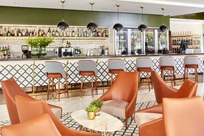 Un área de bar con diversas opciones de asientos, incluyendo sillas y una mesa con una planta.