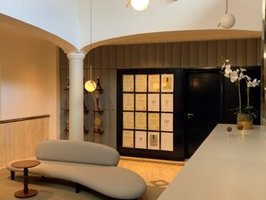 Un vestíbulo moderno con un sofá curvo, una recepción, una pared de premios enmarcados y una orquídea en maceta.