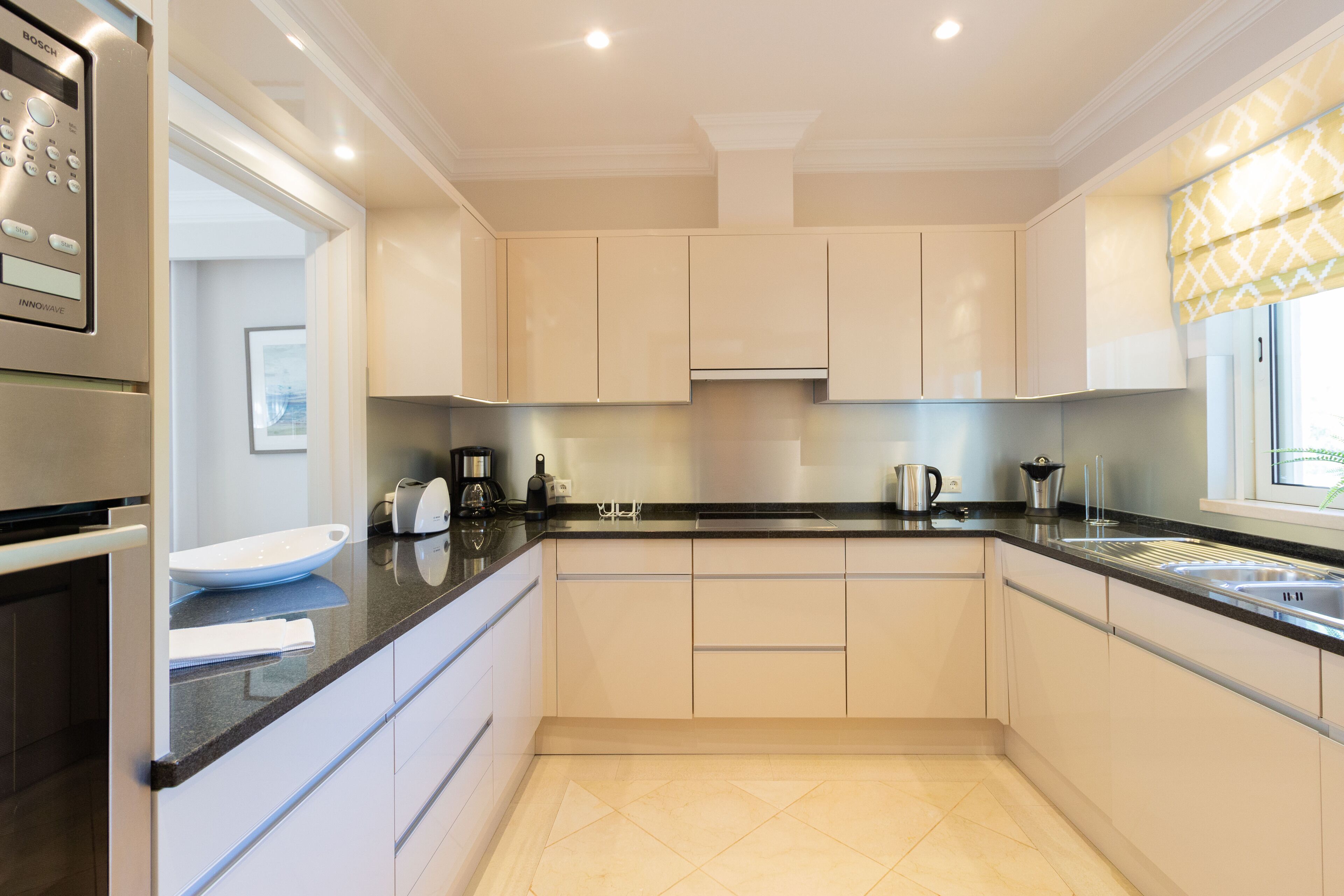 A modern kitchen with white cabinets, a black countertop, and stainless steel appliances.