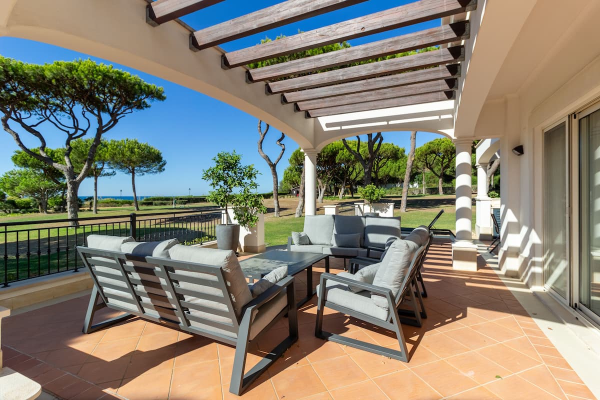 An outdoor patio with a pergola, seating area, and a view of the landscape.
