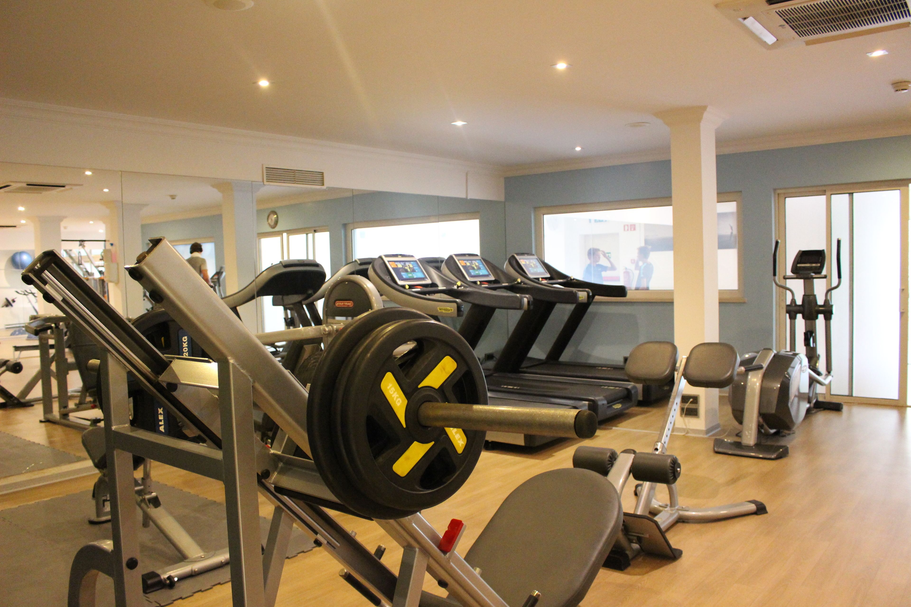 A gym with cardio machines, weightlifting equipment, and a treadmill.