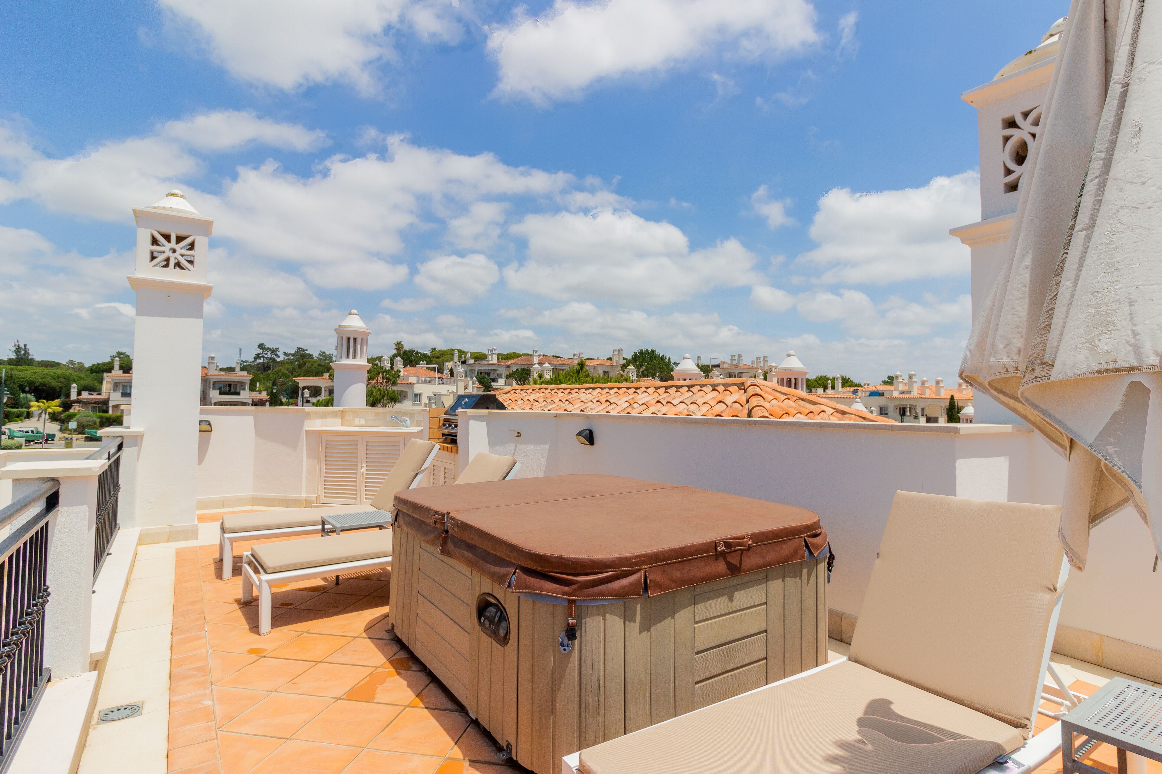 A rooftop terrace with a hot tub, lounge chairs, and a view of the cityscape.
