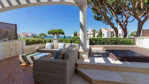 An outdoor patio with wicker furniture, a hot tub, and a view of the sea. - Dunas Douradas Beach Club (Loulé)