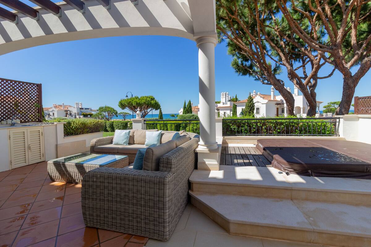 An outdoor patio with wicker furniture, a hot tub, and a view of the sea.