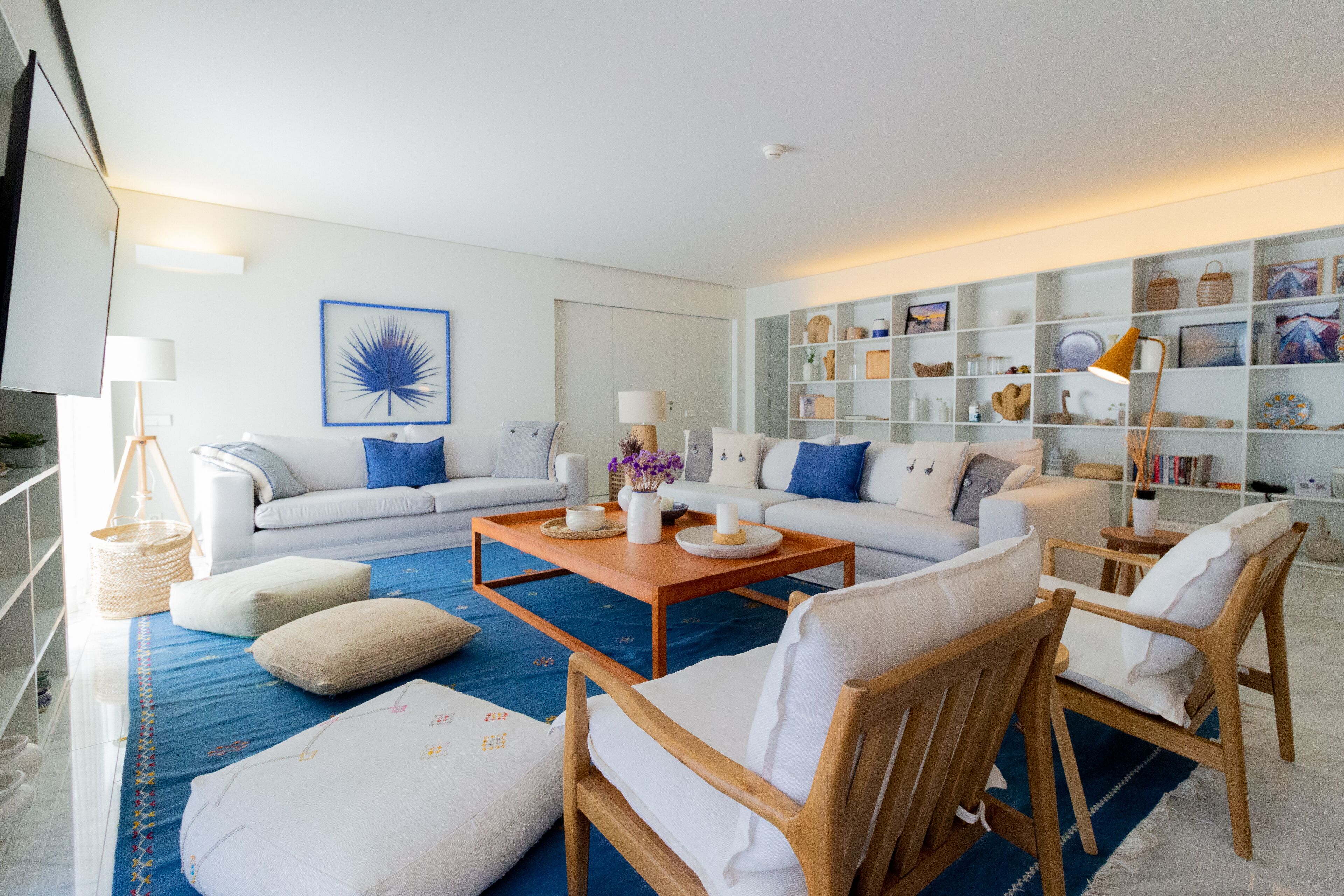 A modern living room with a sofa set, wooden chairs, a coffee table, and a bookshelf.