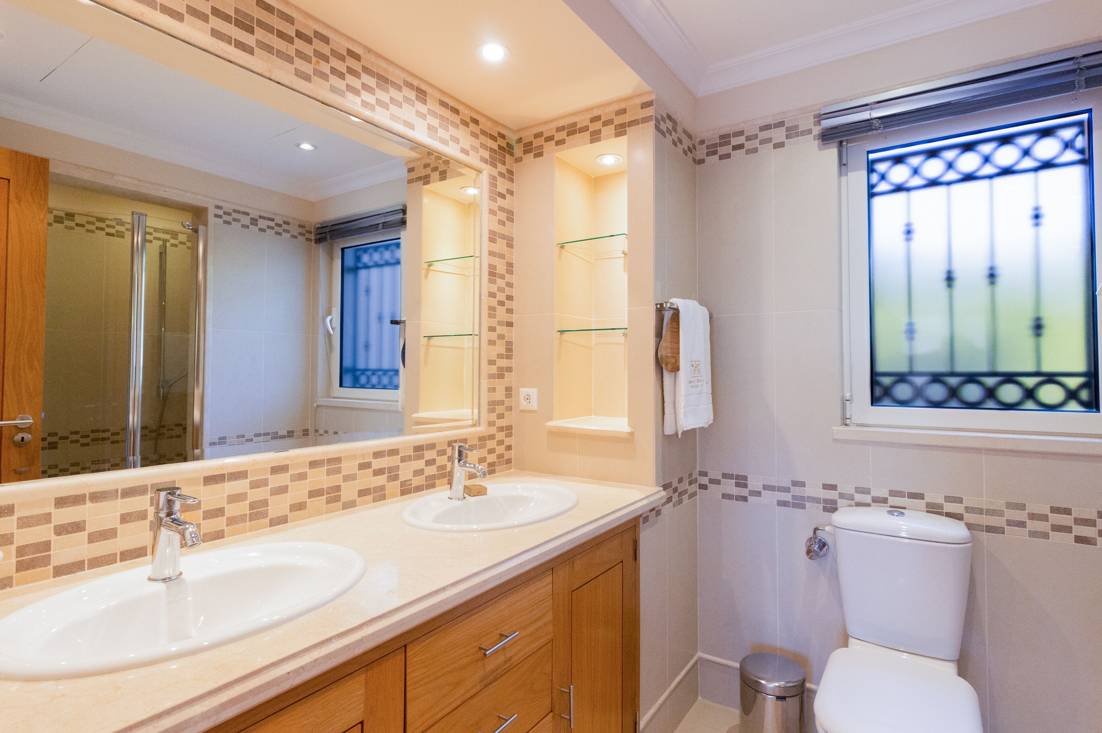 A bathroom with two sinks, a mirror, a shower, and a toilet.