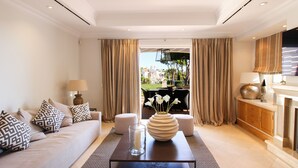 A modern living room with a sofa, a coffee table, and a vase of flowers. - Dunas Douradas Beach Club (Loulé)