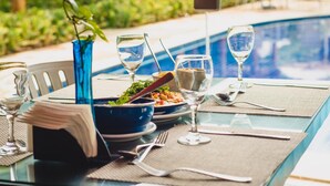A dining table set for two with a bowl of salad, wine glasses, and cutlery. - Tabaobí Smart Hotel (Ipojuca)