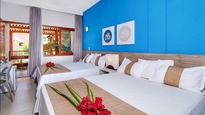A hotel room with two beds, a wooden headboard, a blue accent wall, and a view of the outdoors. - Tabaobí Smart Hotel (Ipojuca)