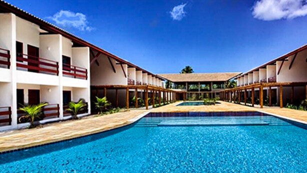 A hotel with a central pool, multiple balconies, and a clear blue sky. - Tabaobí Smart Hotel (Ipojuca)