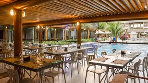A restaurant with outdoor seating overlooking a pool, featuring wooden beams and glass partitions. - Tabaobí Smart Hotel (Ipojuca)