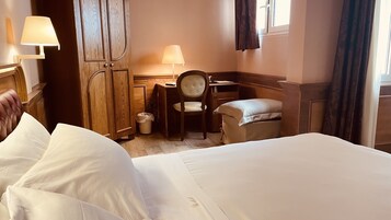Una habitación de hotel con cama, escritorio, silla y lámpara.
