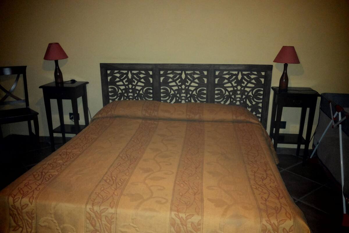 Un lit avec une couvre-lit à motifs, deux tables de chevet avec des lampes et une tête de lit décorative.