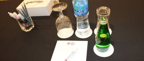 A table with a water bottle, a glass, a pen, and a brochure.