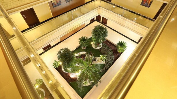 A multi-level atrium with a central garden area, glass railings, and artwork on the walls. - Best Western Plus Salmiya (Salmiya)