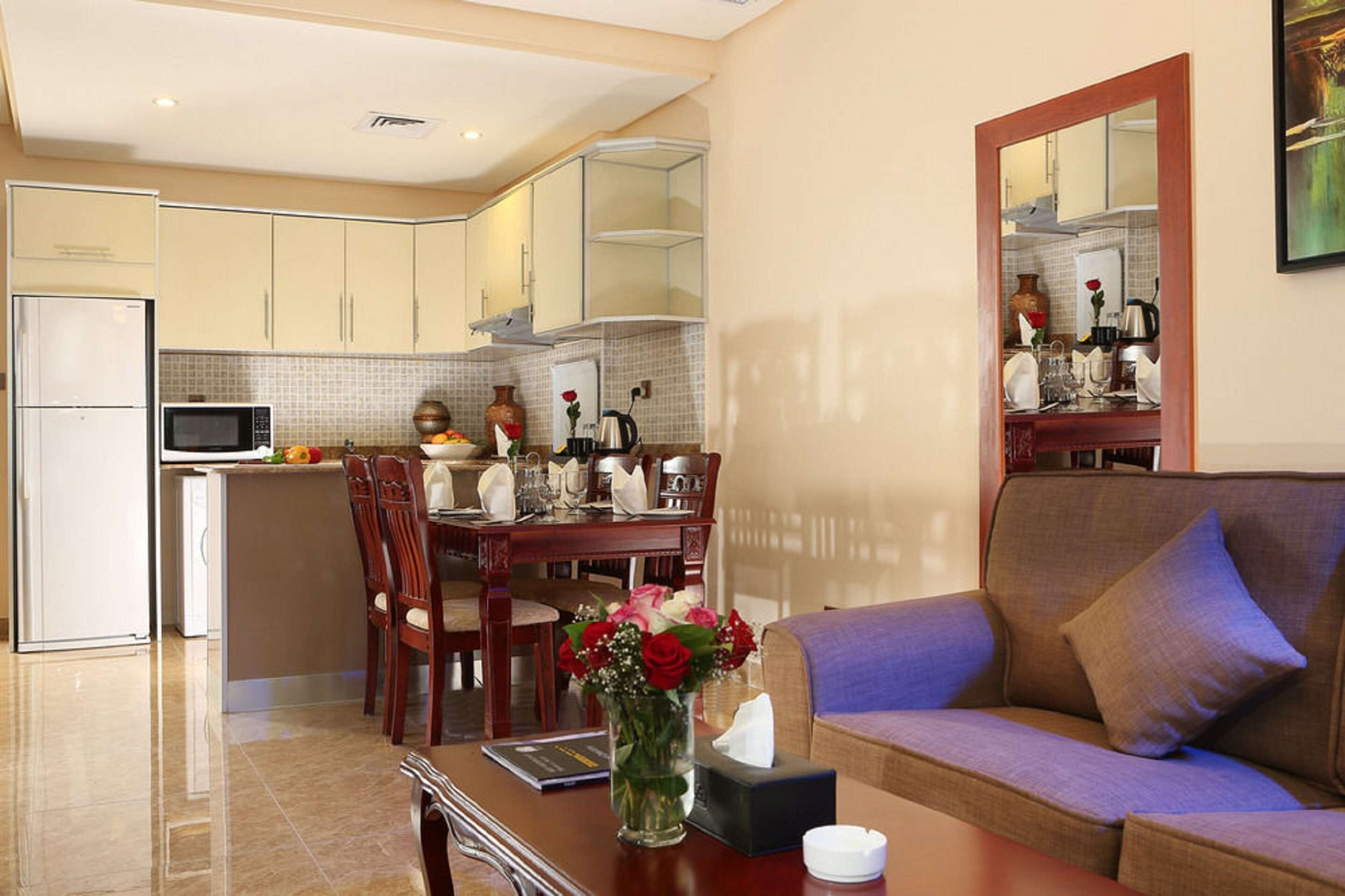 A modern kitchen with a dining area, a sofa, and a vase of flowers.