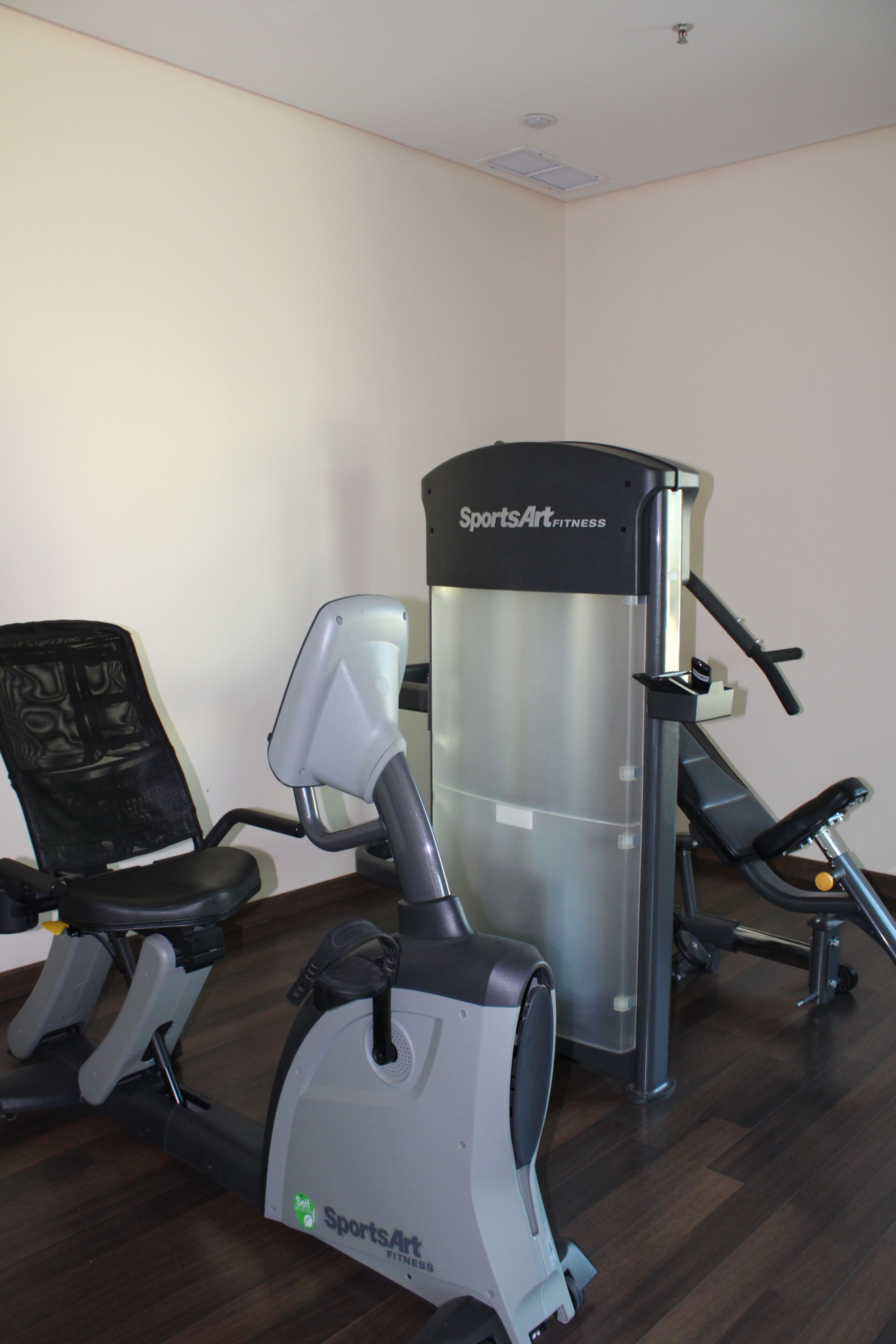 A gym with a stationary bike, an elliptical trainer, and a weight machine.