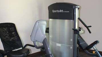 A gym with a stationary bike, an elliptical trainer, and a weight machine.