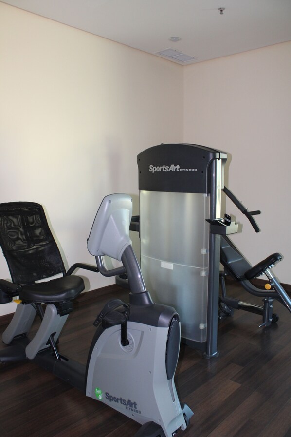Un gimnasio con una bicicleta estática, una máquina elíptica y un equipo de pesas.
