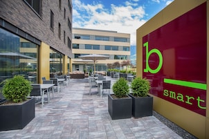 Un patio al aire libre con mesas y sillas, un edificio de ladrillo y una pared con el texto "b smart".