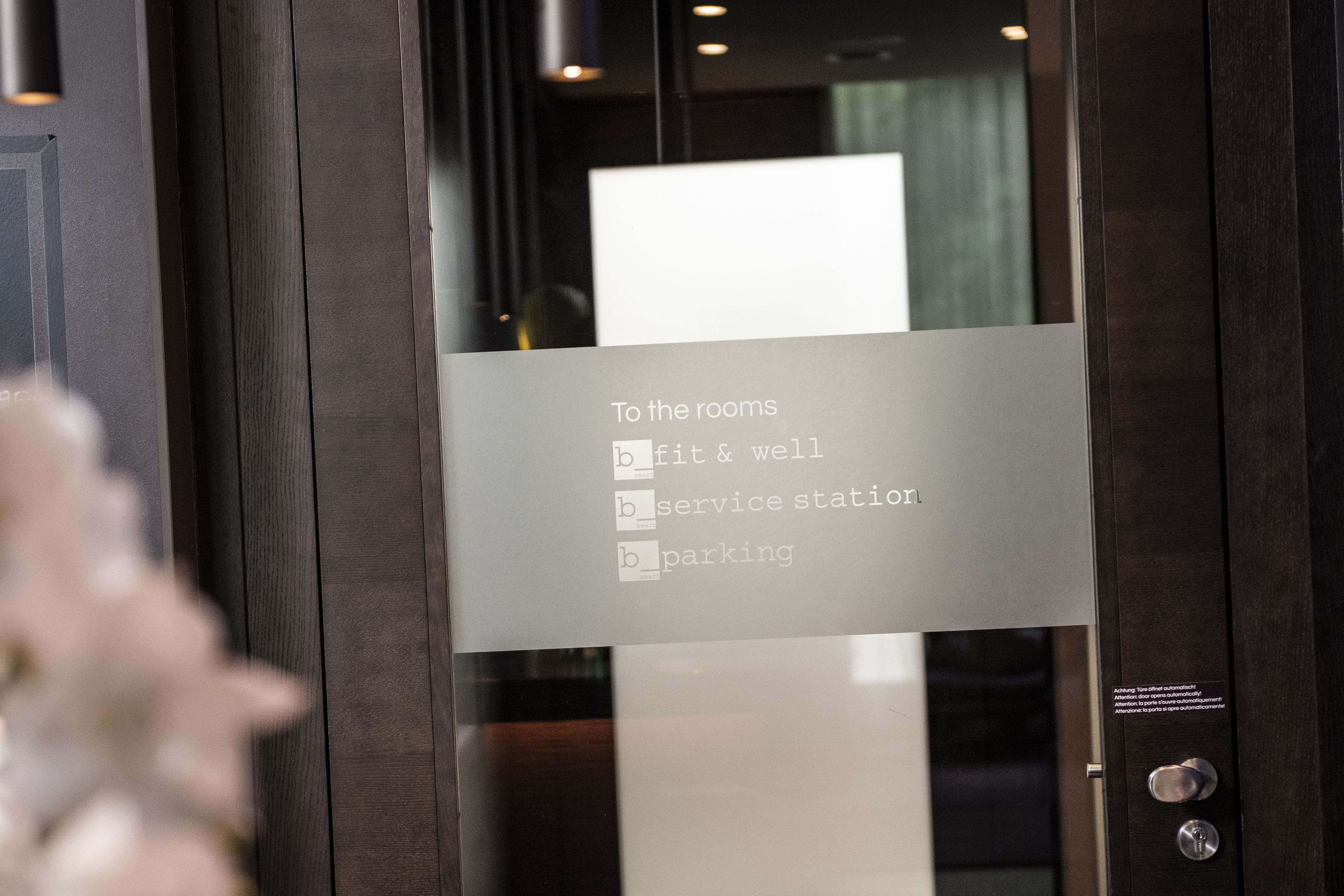 A glass door with a sign listing amenities: fitness & well, service station, and parking.