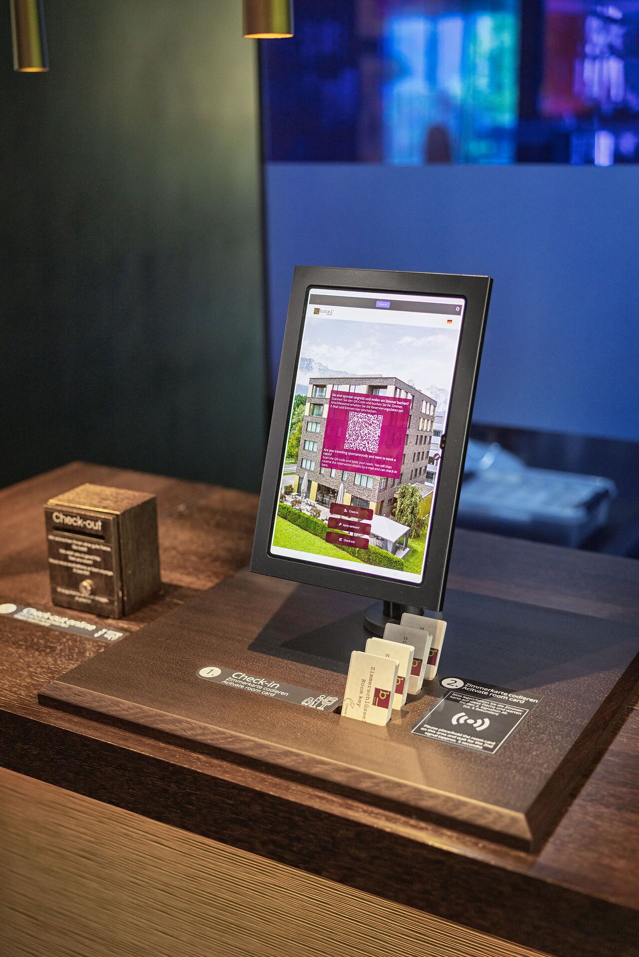 A digital display with a QR code, a check-out box, and a sign for room cards.