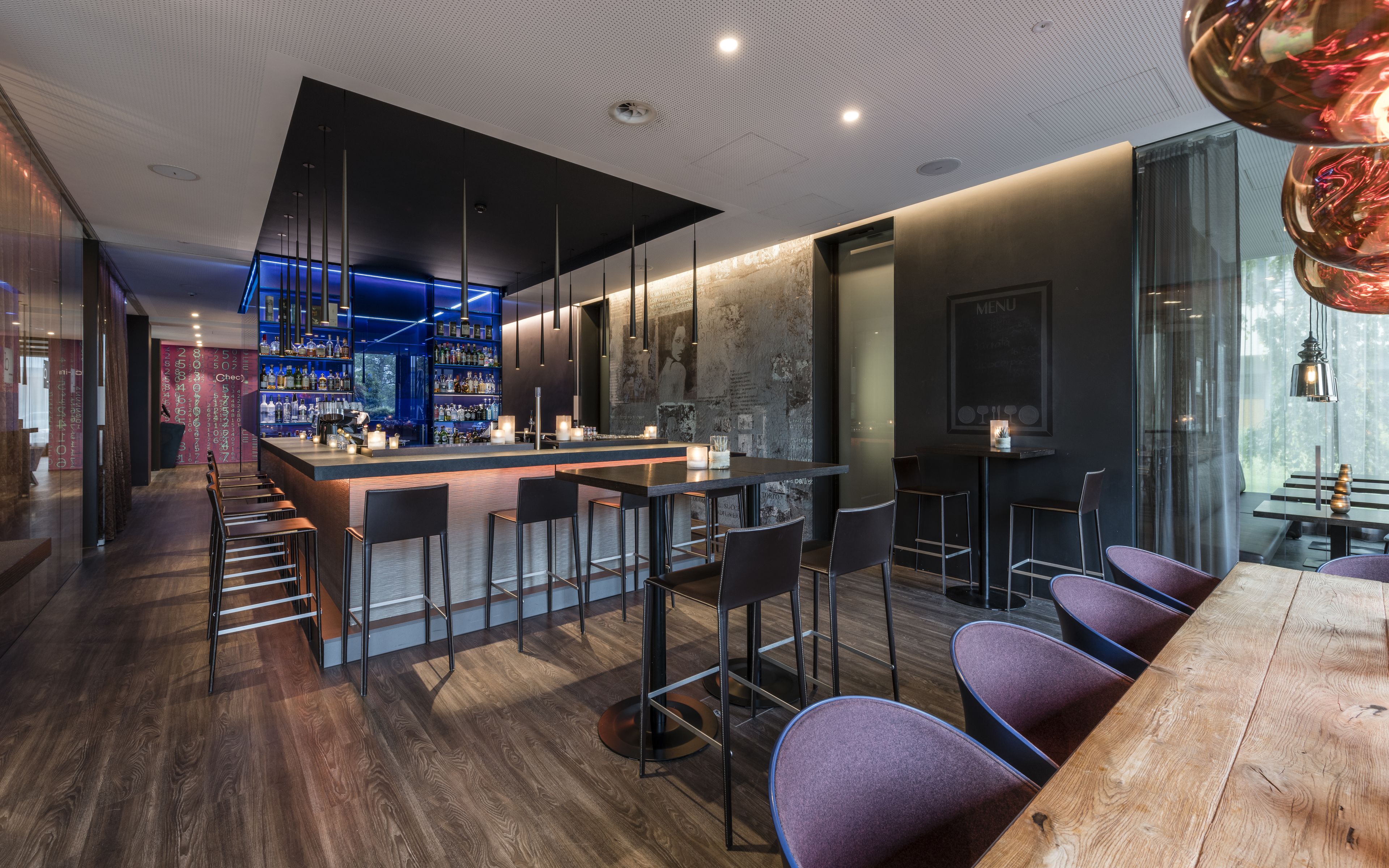 A modern bar area with a bar counter, seating, and a menu sign.