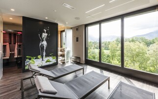 Un moderno spa con un ventanal grande, una obra de arte colgada en la pared y una zona de relajación con camillas de masaje.