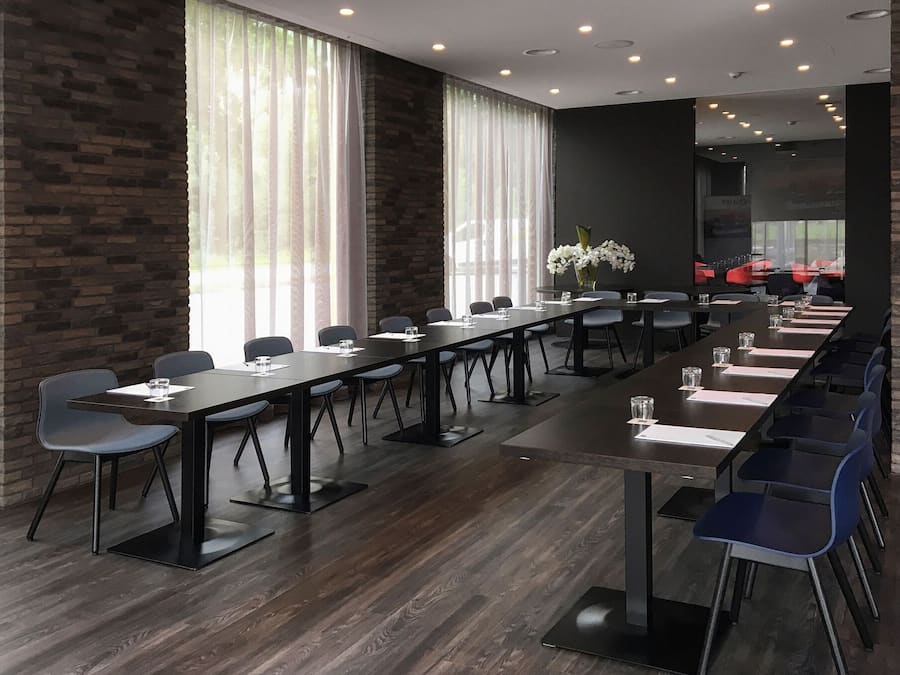 Un salón de conferencias con largas mesas, sillas y una pared de ladrillo.