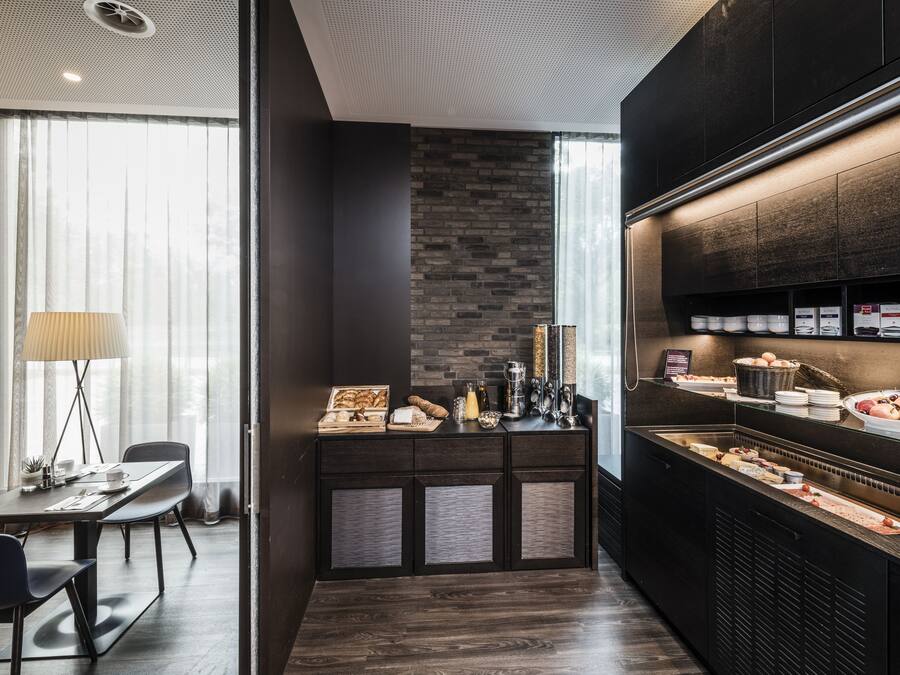A modern kitchen with a brick wall, a dining area with a table and chairs, and a large window providing natural light.