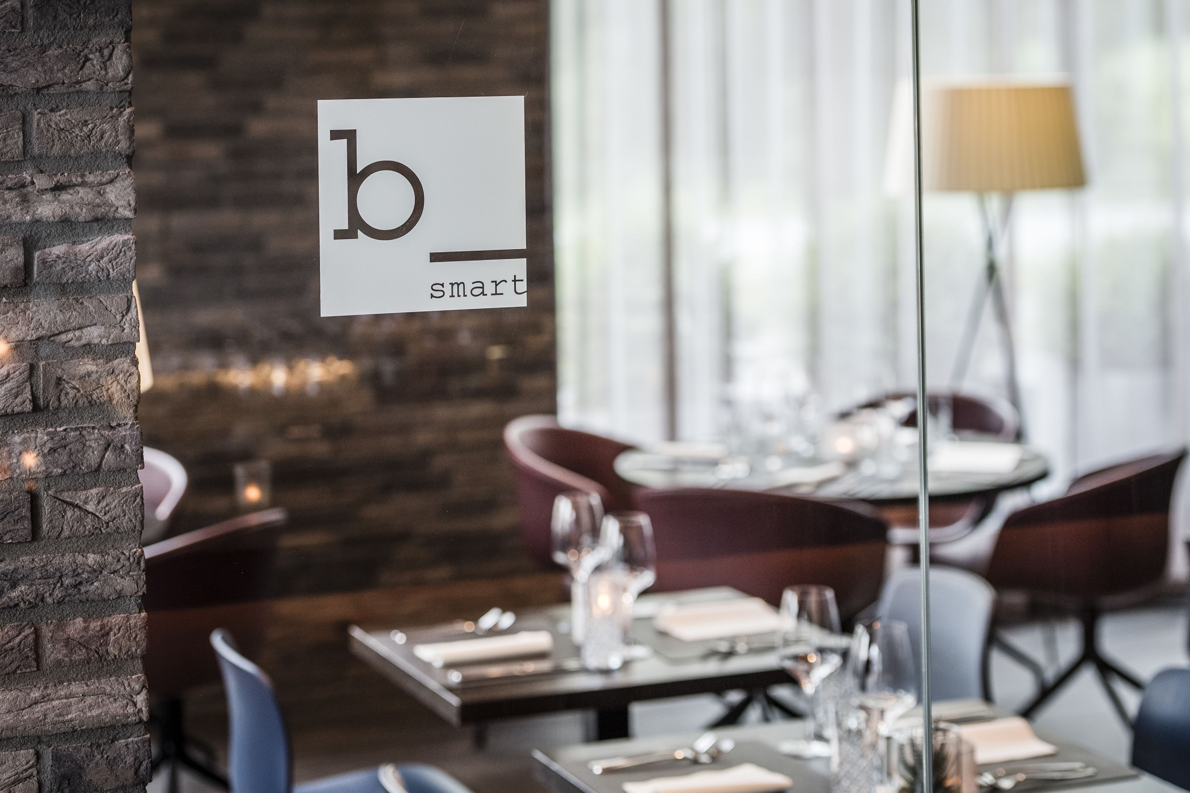 Een restaurantinterieur met een modern design, met een bakstenen muur, houten tafels en comfortabele zitplaatsen.