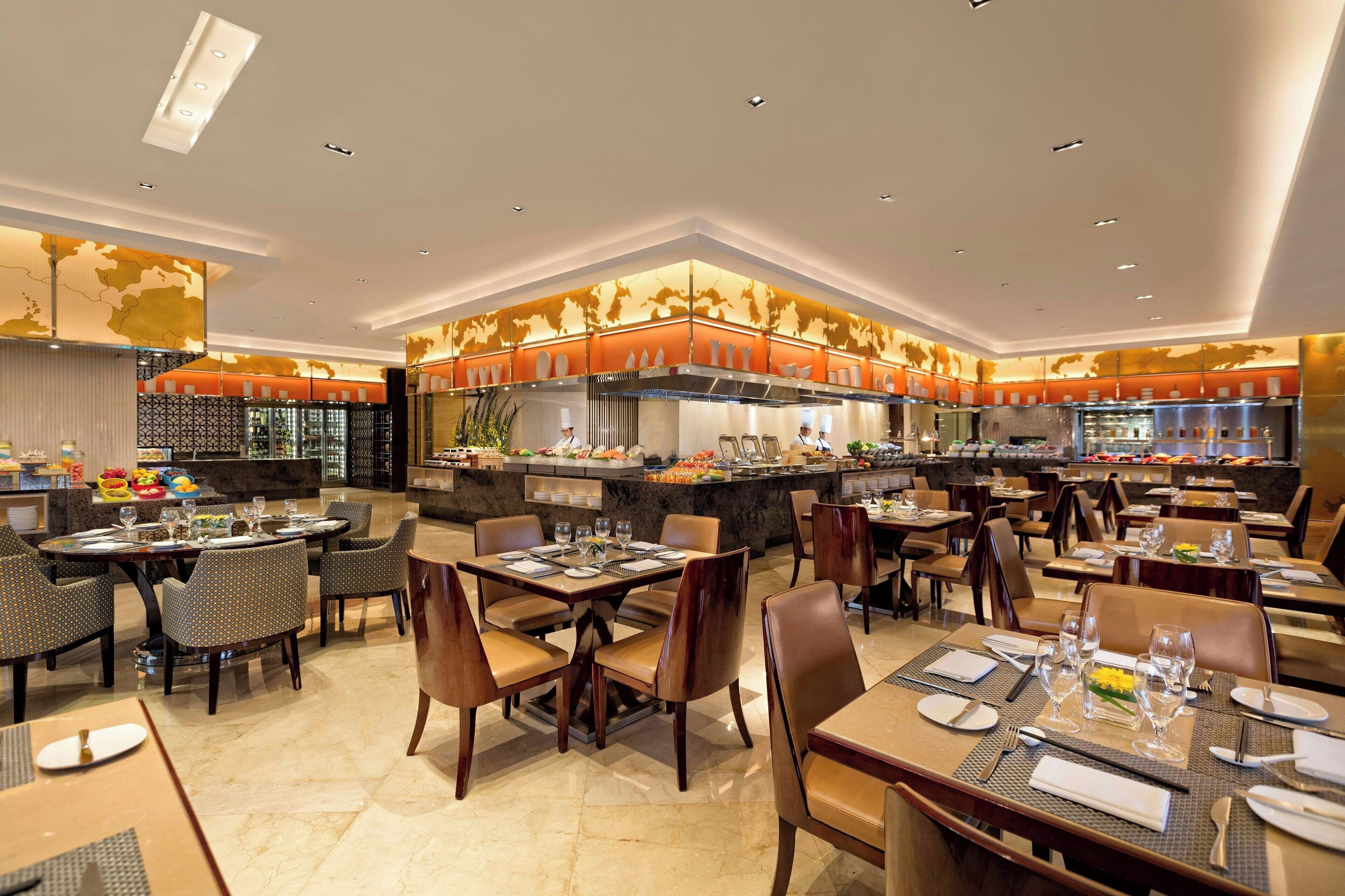 A spacious restaurant with multiple dining areas, a central kitchen, and a buffet.