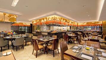 A spacious restaurant with multiple dining areas, a central kitchen, and a buffet.