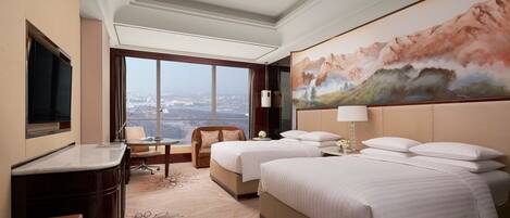 A hotel room with two beds, a desk, a chair, and a large window offering a city view.