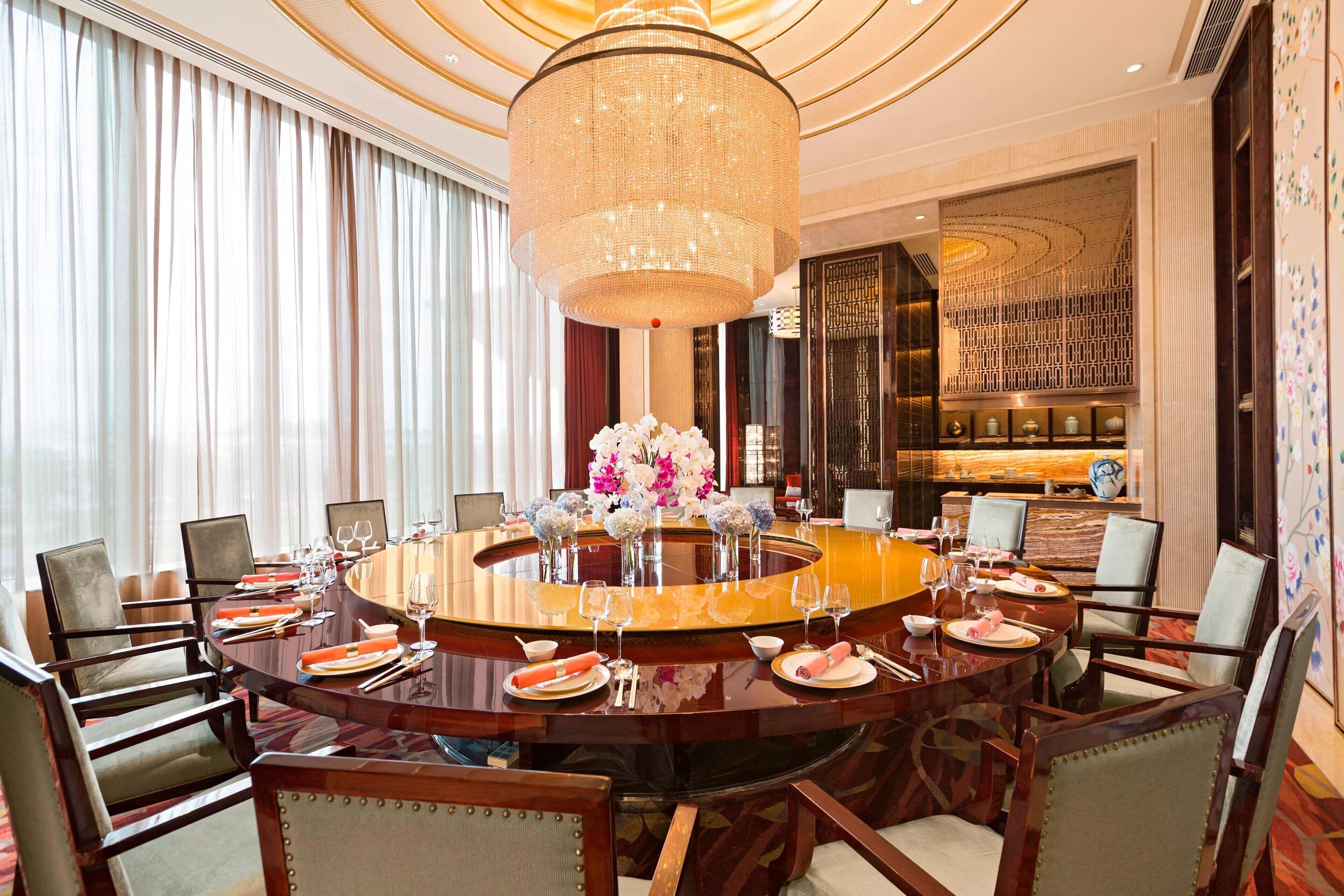 A round dining table with chairs, a chandelier, and a decorative centerpiece.