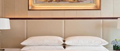 Une chambre d’hôtel avec un grand lit, une table de chevet, une lampe et une œuvre d’art encadrée au mur.