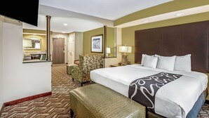 A hotel room with a large bed, a desk with a flat-screen TV, a chair, a desk lamp, and a framed picture on the wall. - La Quinta Inn & Suites by Wyndham Kearney (Kearney)
