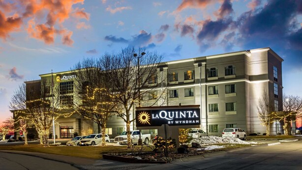 A La Quinta by Wyndham hotel with a large sign, parking lot, and trees with lights. - La Quinta Inn & Suites by Wyndham Kearney (Kearney)