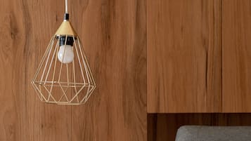 Eine Holzwand mit einer geometrischen Pendelleuchte und einer weißen Schalterleiste.