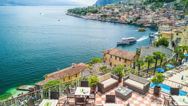 A coastal town with a waterfront promenade, outdoor seating areas, and a view of the sea. - Hotel Splendid Palace (Limone sul Garda)