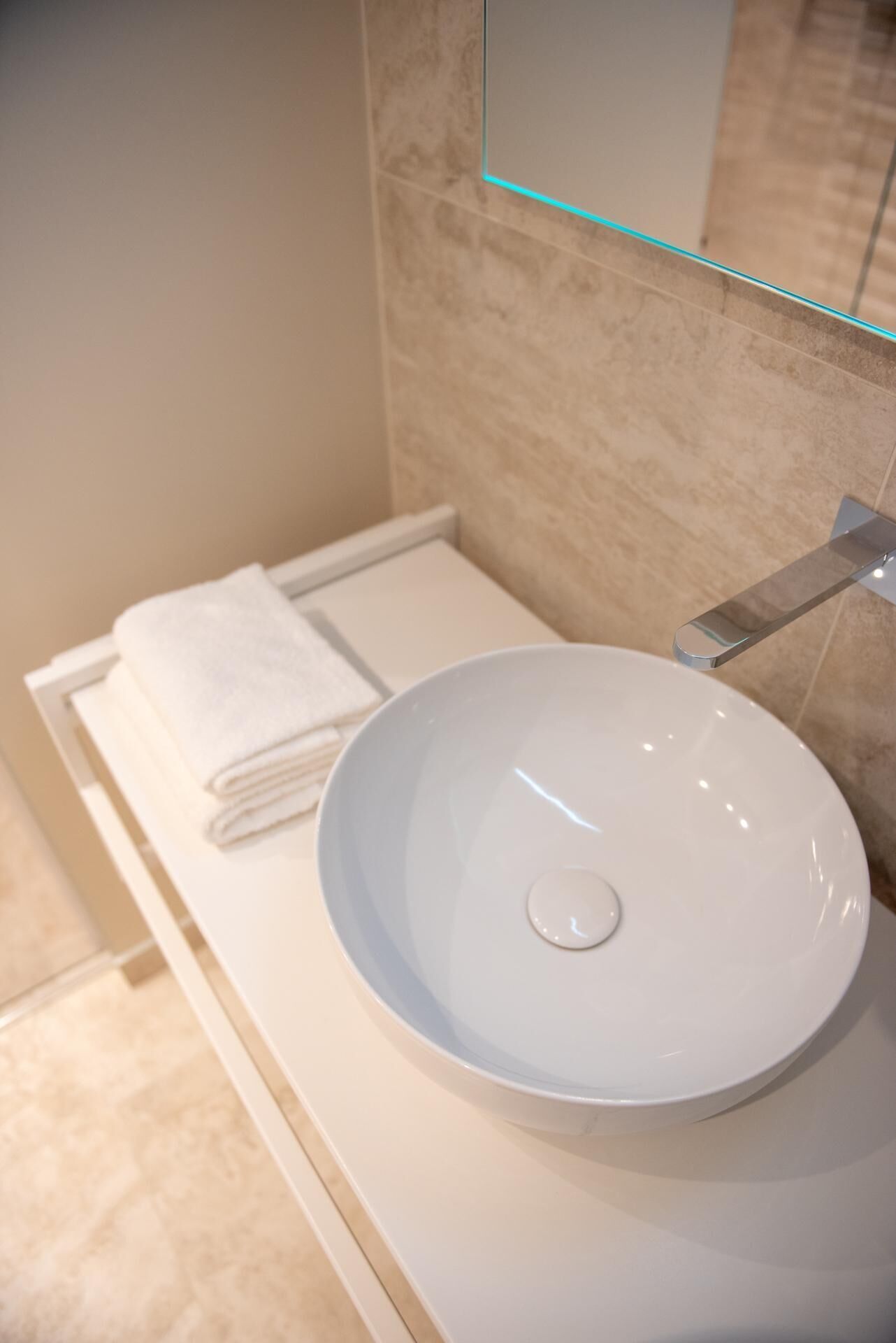 A bathroom with a white sink, a towel, and a mirror.