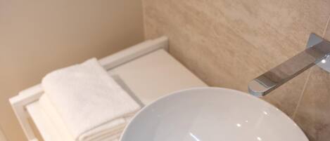 A bathroom with a white sink, a towel, and a mirror.