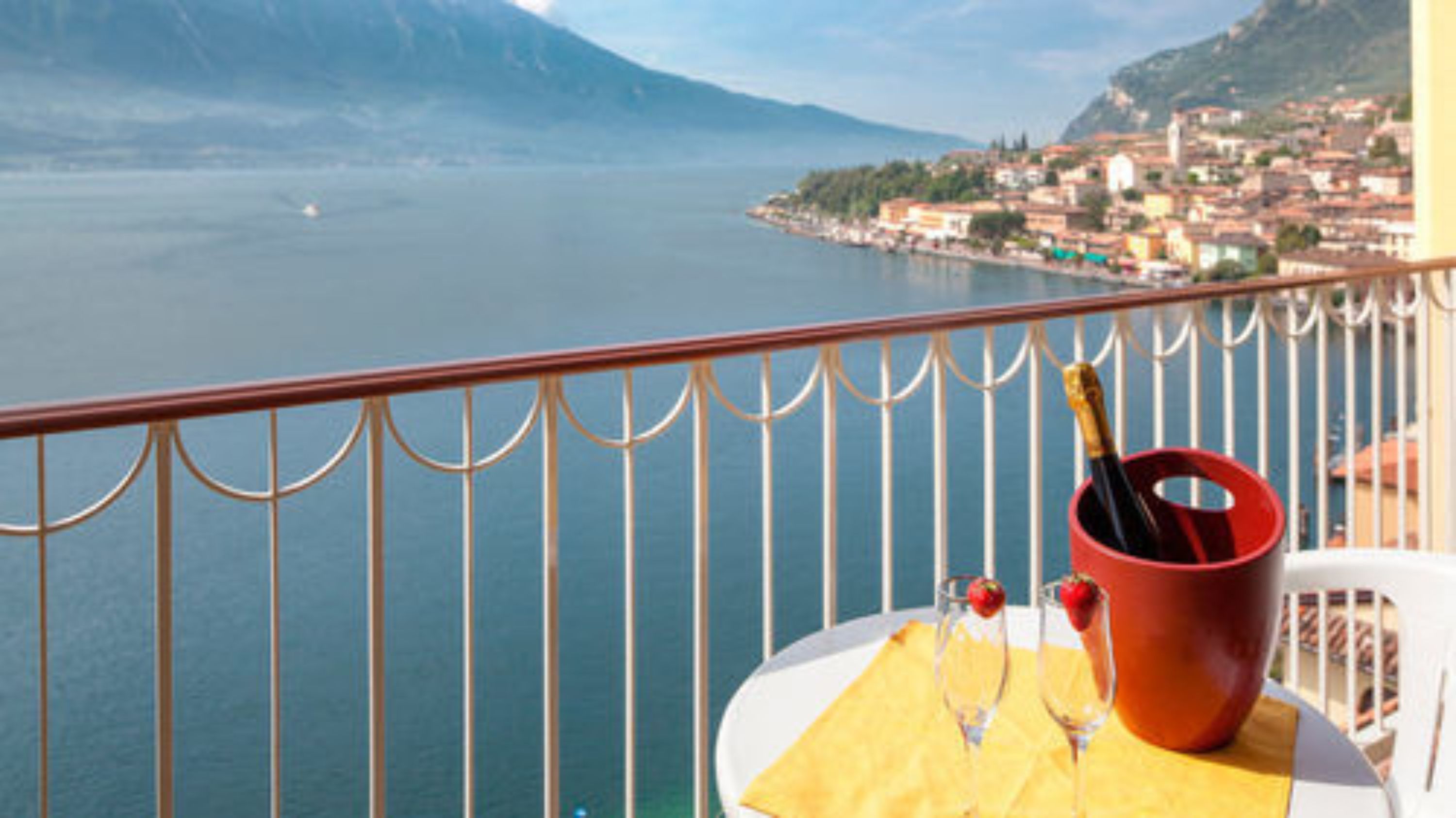 A balcony with a table, a red bucket, and a bottle of champagne.