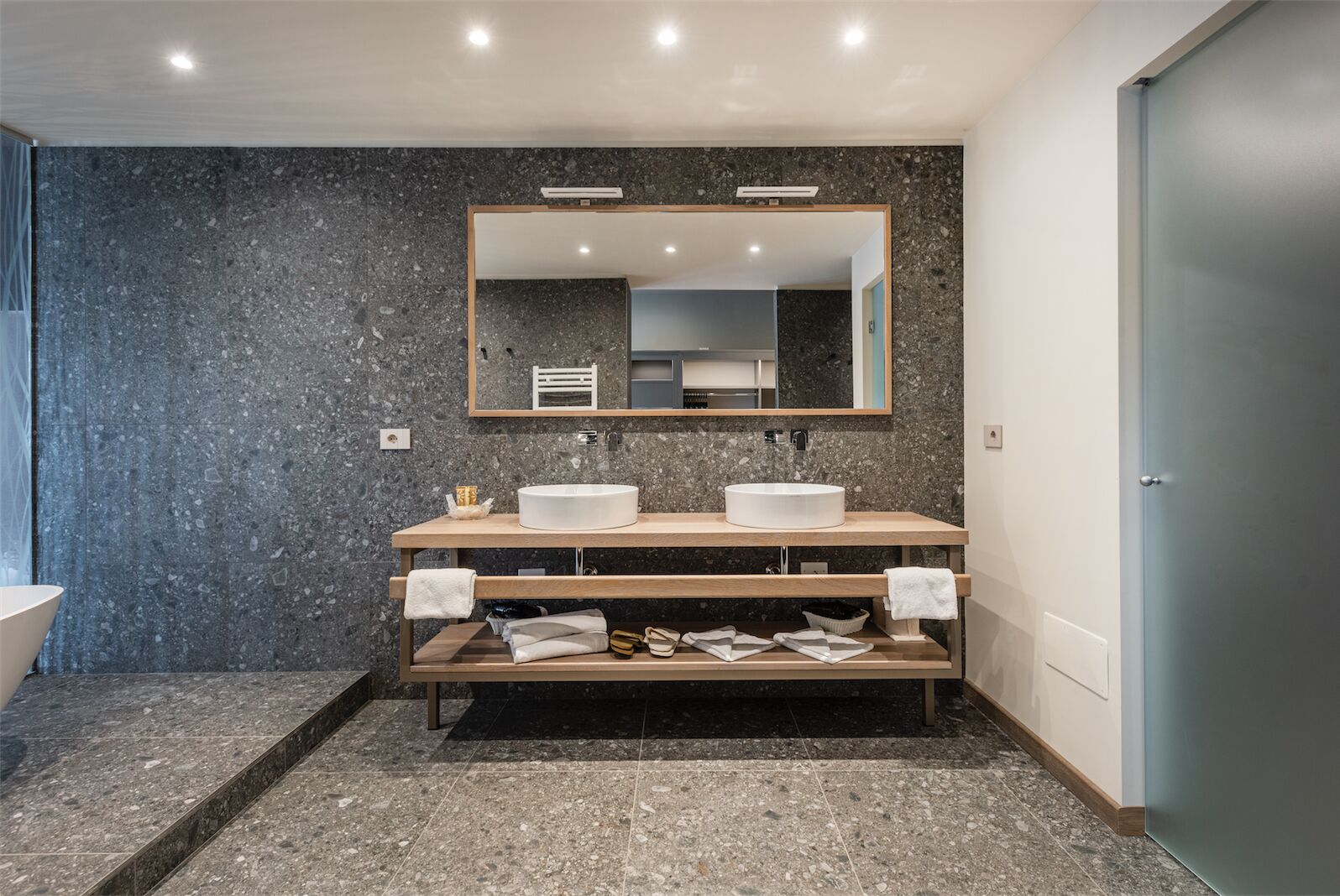 Un baño moderno con dos lavamanos, un espejo grande y un mueble de tocador de madera.