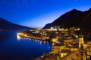 A coastal town at night with illuminated buildings and a calm lake. - Hotel le Palme (Limone sul Garda)