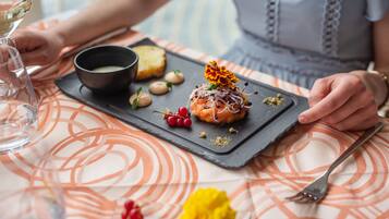 A dining table with a black slate serving tray holding a dessert, a bowl of soup, and some nuts.