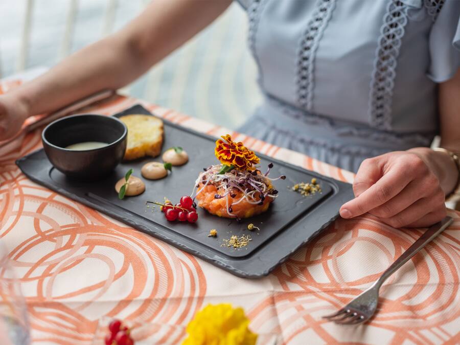 A dining table with a black slate serving tray holding a dessert, a bowl of soup, and some nuts.