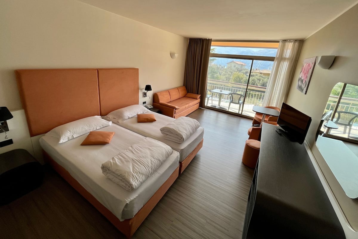 Une chambre d’hôtel avec deux lits, un canapé, une télévision et un balcon avec vue.